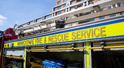 A fire engine with the words Warwickshire Fire &amp; Rescue Service on the side and a ladder along the top