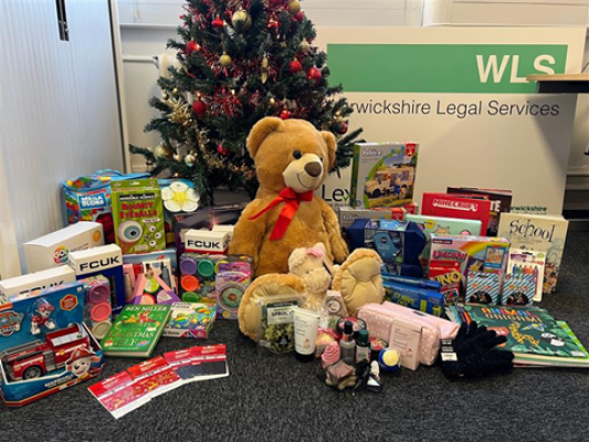 Donations from WLS in front of a Christmas Tree and the WLS logo