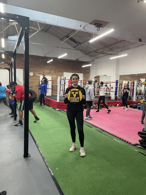 young girl stoon in a gym holding the child friendly Warwickshire logo.